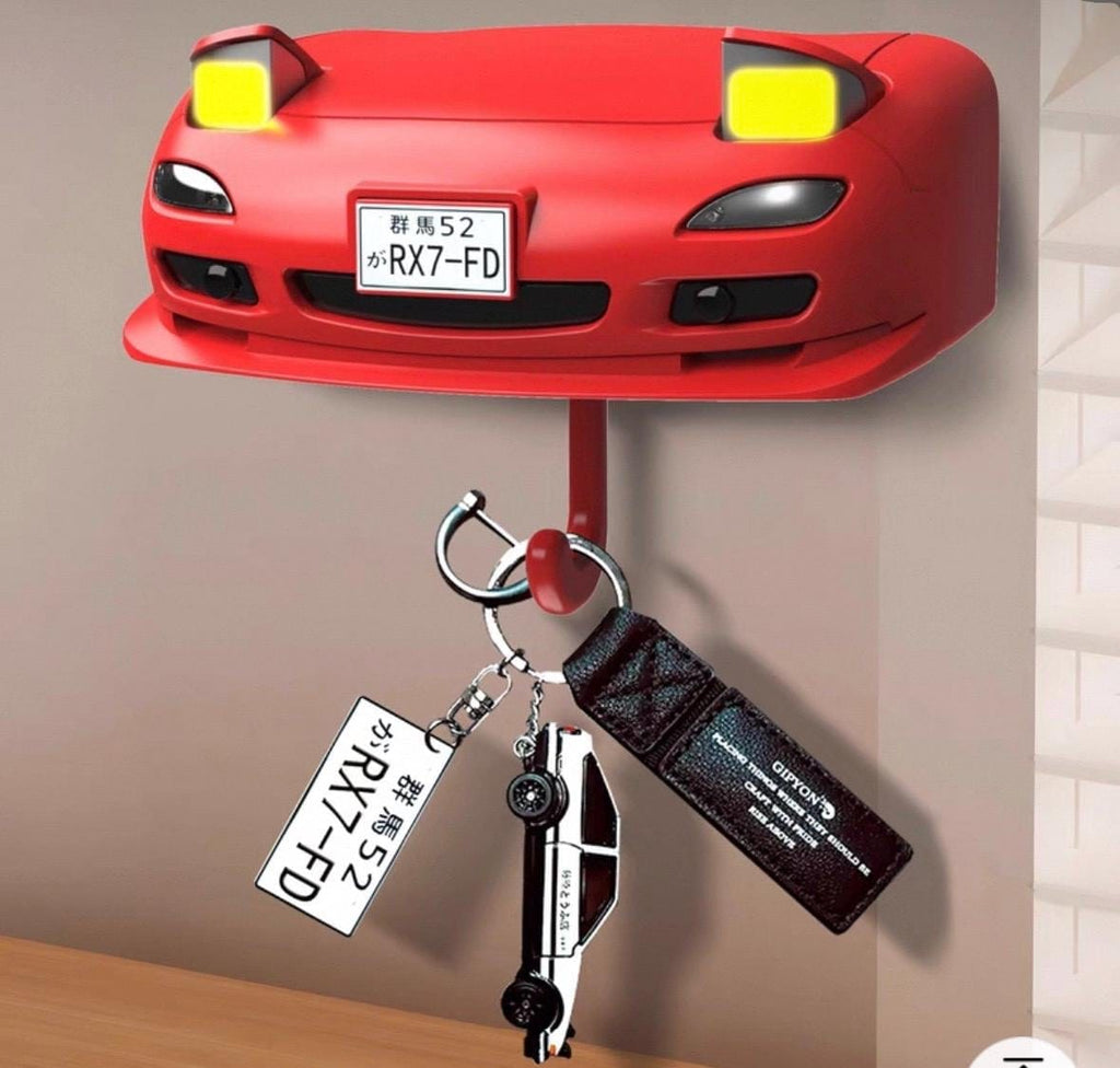 Red car-shaped key holder with a keychain attached on a neutral background