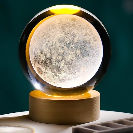 Moon lamp with a textured surface on a wooden base against a dark green background
