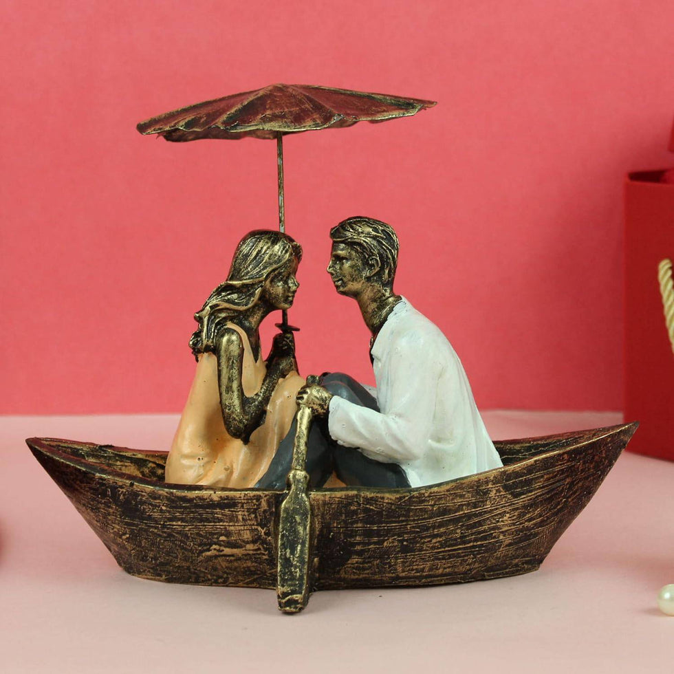 Statue of a couple in a boat with an umbrella on a pink background