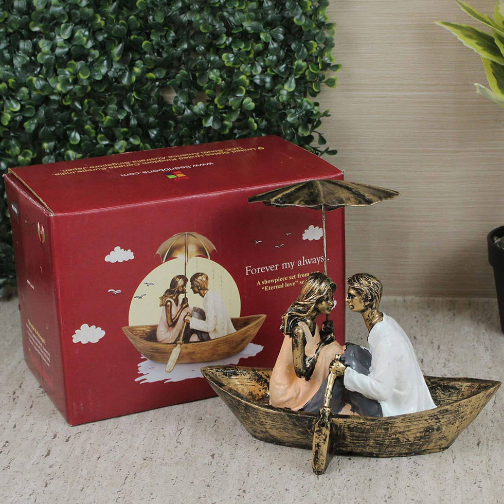 Decorative figurine of a couple in a boat with an umbrella, next to a red box with a similar design.